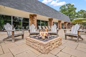 a fire pit with chairs and umbrellas in front of a building